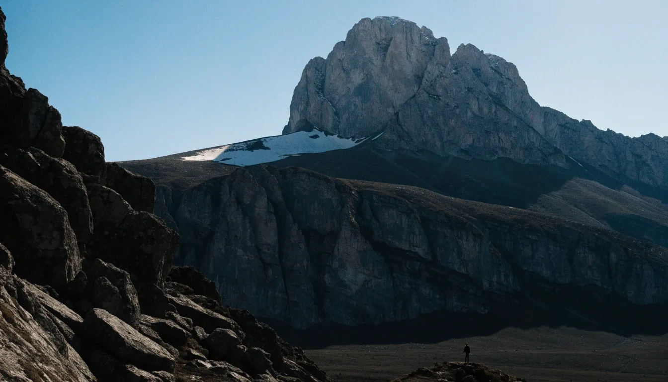 Picos de Europa: macizo de caliza bajo luz dura con un senderista diminuto en una hombrera